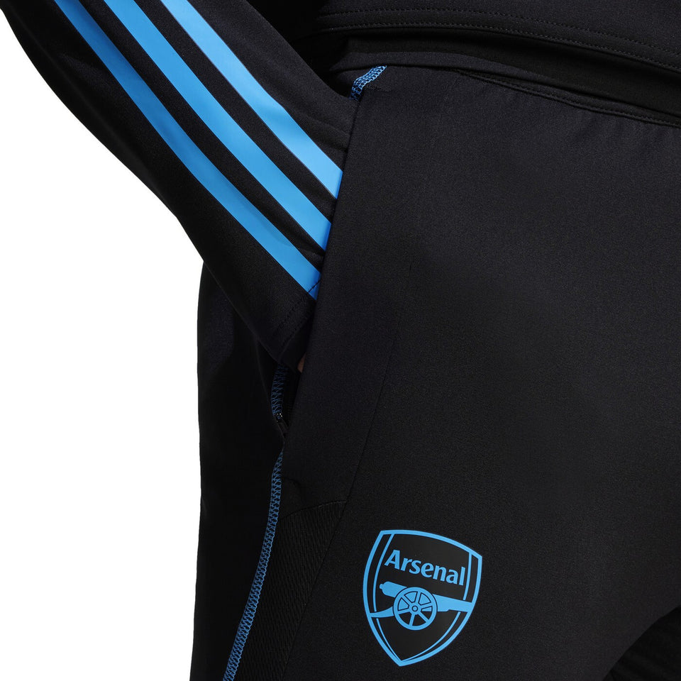 Close-up of black 2023 24 Arsenal football tracksuit set with blue stripes and Arsenal logo on pants