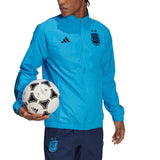 Man wearing Argentina presentation tracksuit 2022 light blue jacket with Argentina crest and navy pants holding soccer ball