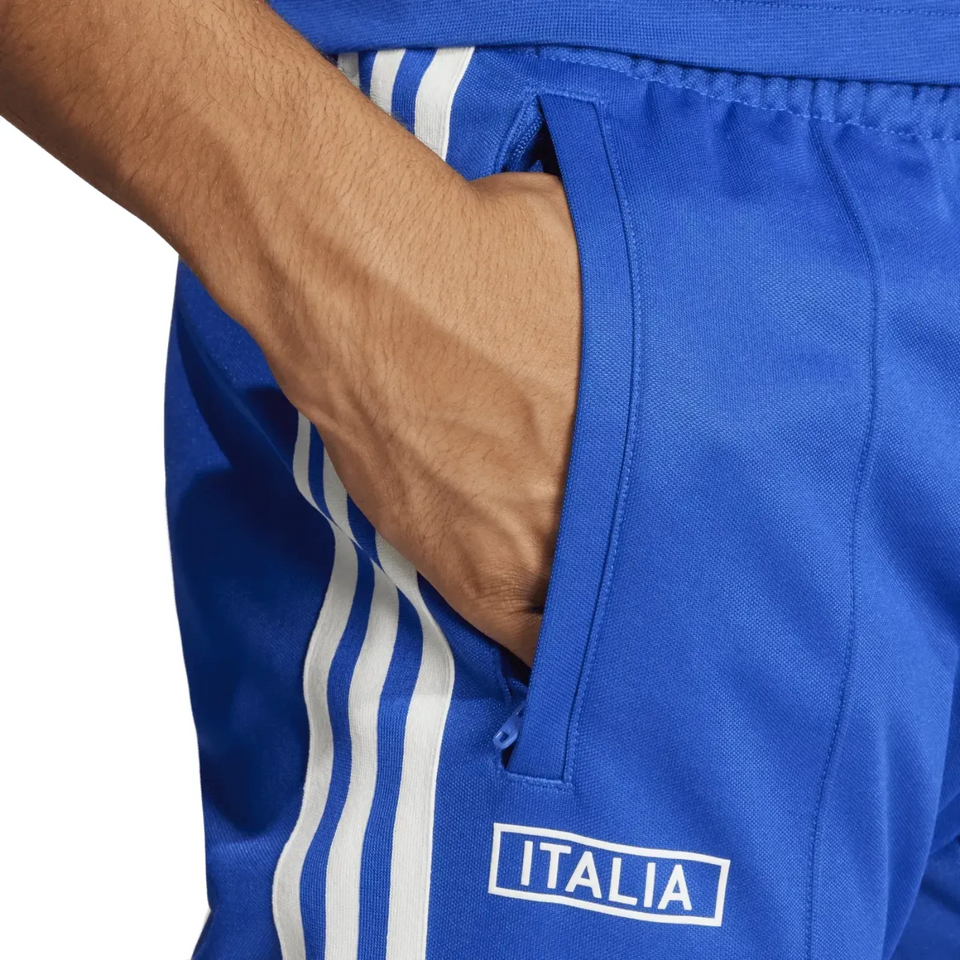 Close up of blue Italy Adidas Originals tracksuit pants with hand in pocket white three stripes and Italia logo