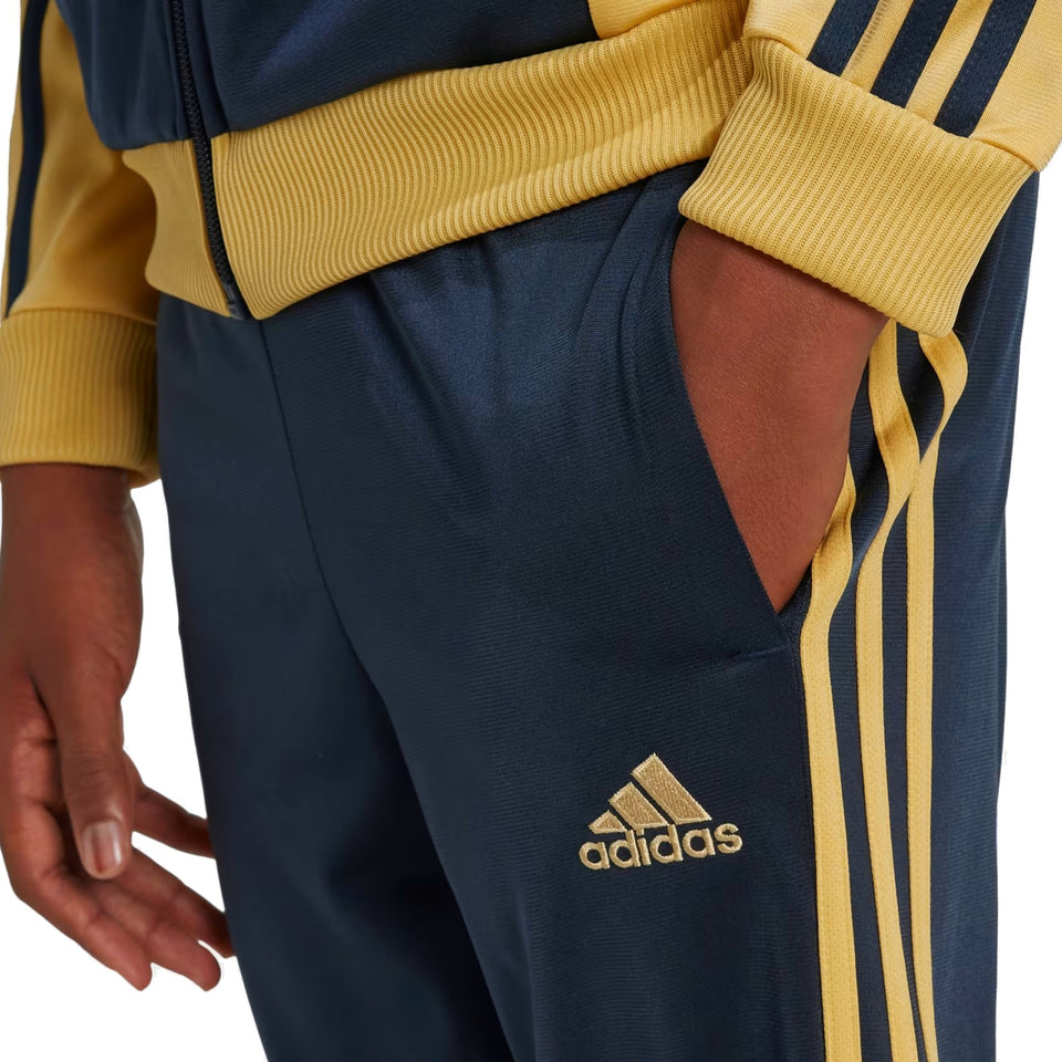 Close-up of kids Juventus tracksuit 2024 navy and gold Adidas pants with hand in pocket