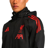 Liverpool FC black rain jacket 2025 on model showing hood, zip front, red LFC crest and shoulder stripes