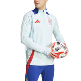 Man wearing Spain national team tracksuit for sale in light blue and blue with red accents holding a soccer ball