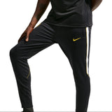 A man wearing a black Nike Chelsea FC training kit with yellow accents, featuring a short-sleeve top with a 'Bingx' sponsor logo and matching track pants, set against a plain white background.