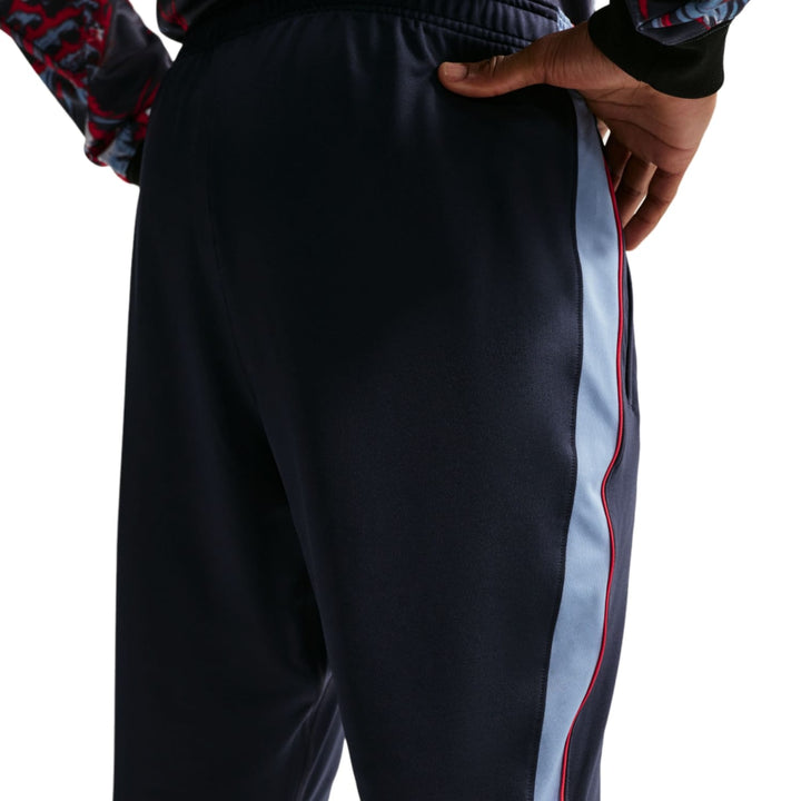 Navy blue Nike soccer tracksuit set with red and light blue side stripes for adults, featuring a technical design.