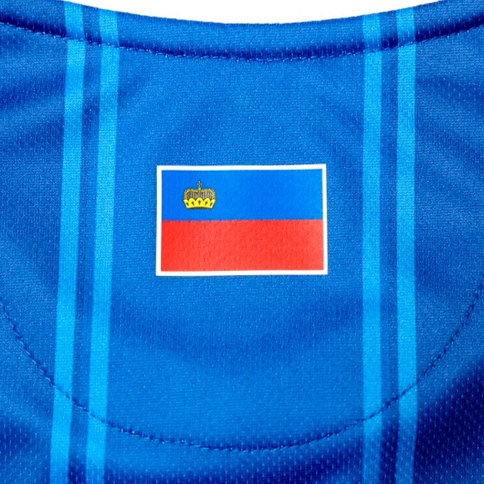Close-up of Liechtenstein home soccer jersey 2024 with blue fabric and flag emblem on chest