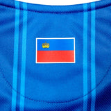 Close-up of Liechtenstein home soccer jersey 2024 with blue fabric and flag emblem on chest