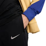 Close-up of FC Barcelona gold tracksuit 2024 featuring stylish design and Nike logo on pants