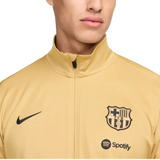 Close-up of FC Barcelona gold tracksuit 2024 featuring the club logo and Nike branding