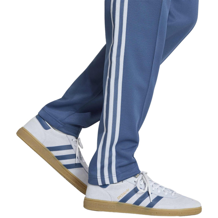 White Adidas sneakers with blue stripes and gum sole, featuring a low-top design.