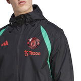 Manchester United black rain jacket 2023 with red logos and green side panels on SoccerTracksuits.com