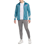 Man wearing Atletico Madrid soccer tracksuit for sale with teal jacket and gray pants