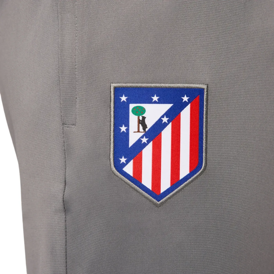 Close-up of Atletico Madrid soccer tracksuit for sale with embroidered club badge on gray fabric