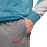 Atletico Madrid soccer tracksuit for sale featuring grey pants with red Nike logo and blue jacket sleeve 