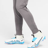 Close-up of gray pants and white Nike cleats worn with kids Atletico Madrid tracksuit