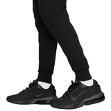 Model wearing Liverpool FC black tech fleece pants with tapered cuffed ankles paired with black Nike sneakers