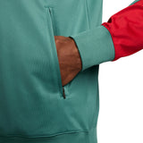 Close-up of a hand in the pocket of a green and red Liverpool FC presentation tracksuit 2024 25 jacket