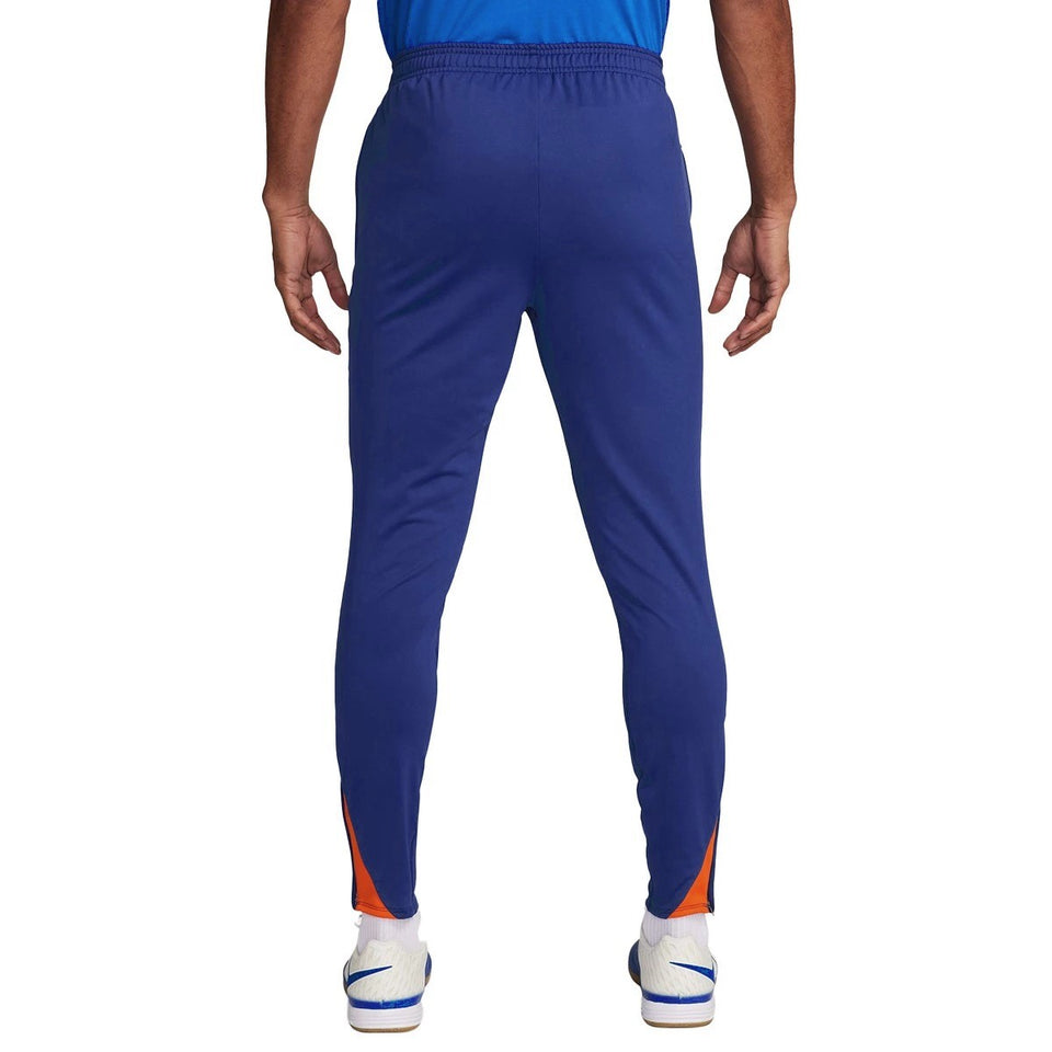 Back view of Nike Netherlands training tracksuit blue pants with orange accents and white sneakers