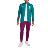 Official PSG Nike tracksuit 2024 with teal jacket and purple pants worn by man in white sneakers