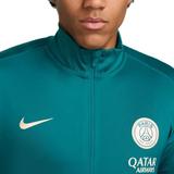 Close-up of official PSG Nike tracksuit 2024 jacket in teal with Paris Saint-Germain badge and Nike logo