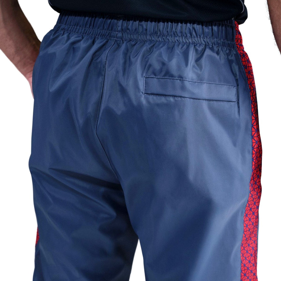 Paris Saint-Germain woven tracksuit men's navy track pants rear view with elastic waist red patterned side stripe and back pocket