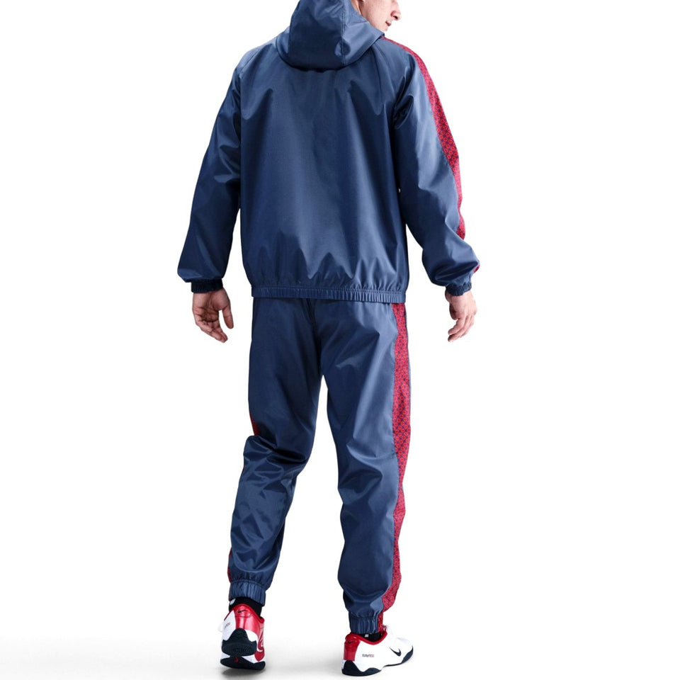 Model wearing Paris Saint-Germain woven tracksuit men's navy hooded jacket and matching pants with red side stripe