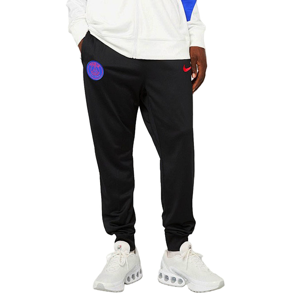 Black PSG tracksuit pants with purple crest and red Nike swoosh worn with white sneakers PSG Nike Total 90 tracksuit 2025 26
