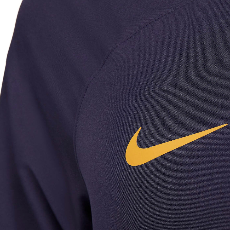 Close-up of yellow Nike logo on navy blue fabric of Nike PSG soccer tracksuit for men