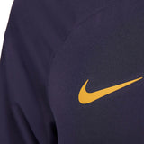Close-up of yellow Nike logo on navy blue fabric of Nike PSG soccer tracksuit for men