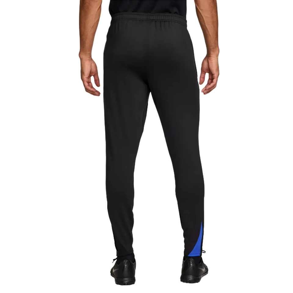 Back view of Nike PSG UCL Total 90 tracksuit pants in black with blue accents for soccer enthusiasts