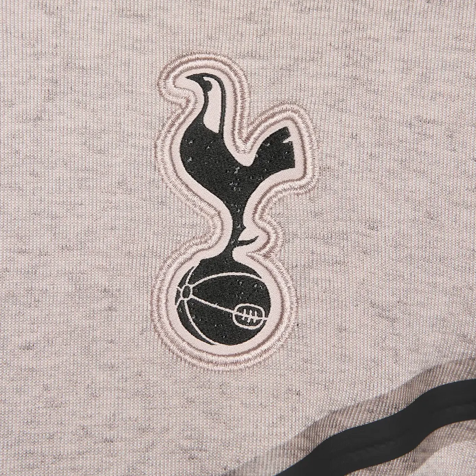 Tottenham Hotspur Tech Fleece tracksuit close-up of embroidered club logo in black and white on gray fabric