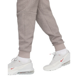 Close-up of gray pants from Tottenham Hotspur Tech Fleece tracksuit worn with white Nike sneakers