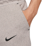 Close-up of gray Tottenham Hotspur Tech Fleece tracksuit pants with black Nike logo and hand in pocket