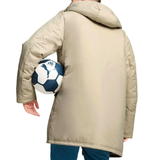 Man holding a soccer ball wearing an Olympique Marseille Puma winter jacket in beige color
