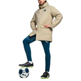 Olympique Marseille Puma winter jacket in gold worn over blue pants, model standing on a soccer ball