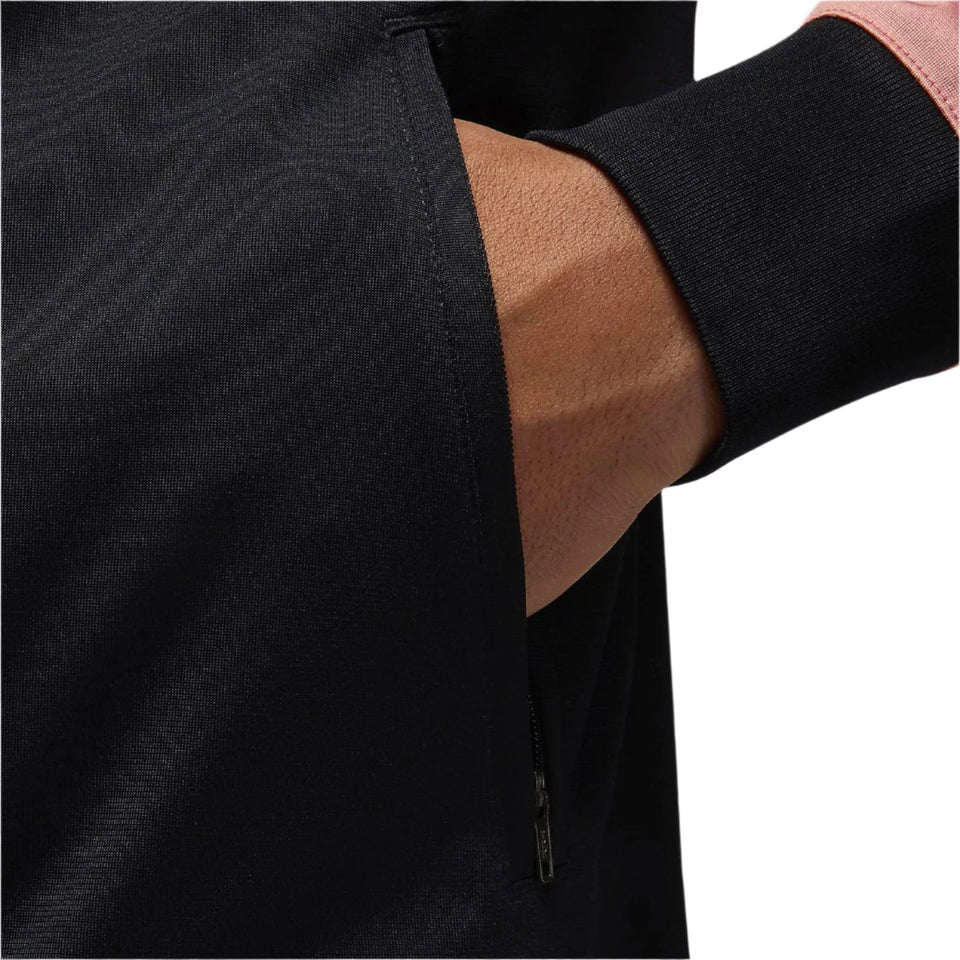 Close-up of hand in zippered pocket of black PSG Champions League tracksuit jacket with ribbed cuff