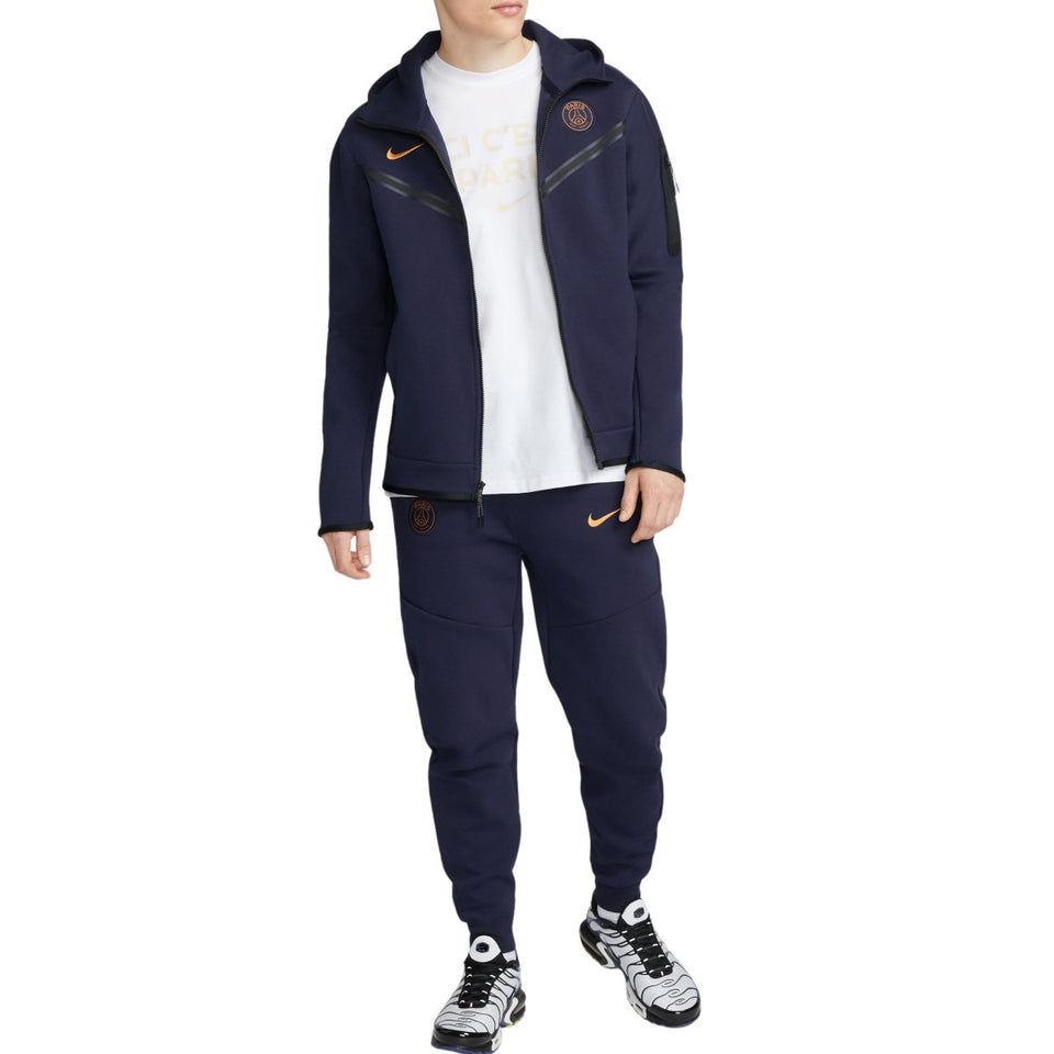 Man wearing navy blue PSG tech fleece tracksuit 2023 with zip-up hoodie and matching pants