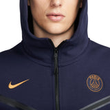 Close-up of navy PSG tech fleece tracksuit 2023 hoodie with Paris logo and orange Nike swoosh