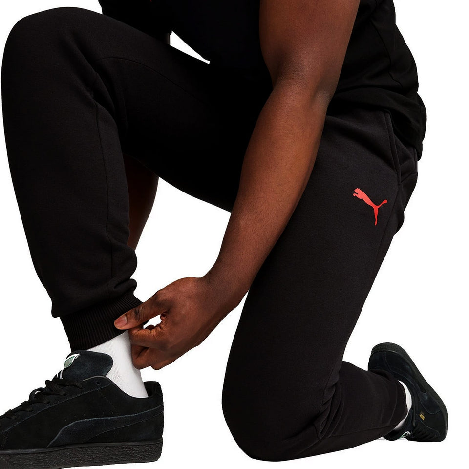Black Puma tracksuit pants with red logo worn by man, part of AC Milan fan apparel 2024 25 collection