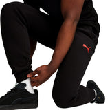 Black Puma tracksuit pants with red logo worn by man, part of AC Milan fan apparel 2024 25 collection