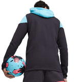 Back view of man wearing Puma Man City hooded tracksuit holding blue and black soccer ball