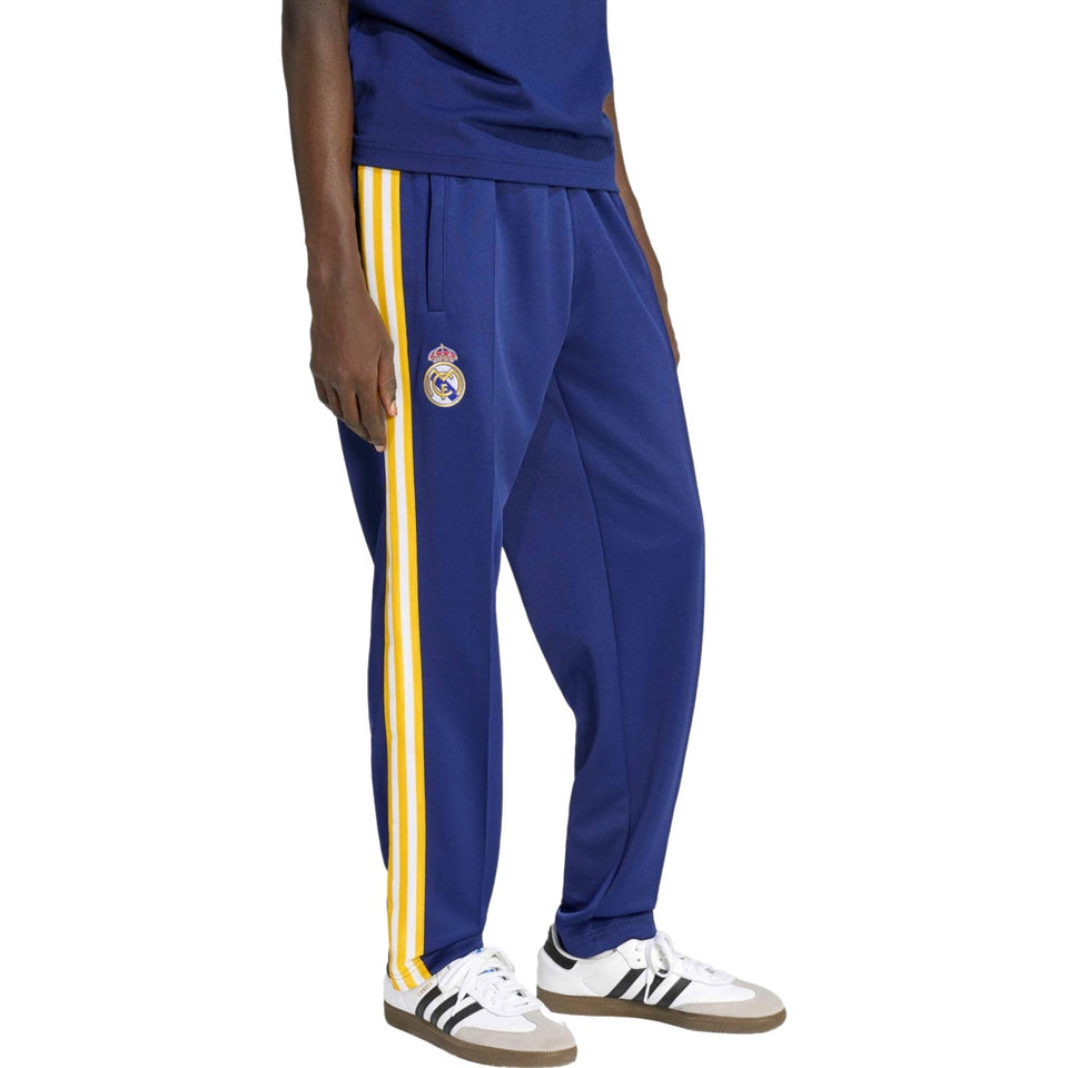 Blue Adidas Originals x Real Madrid tracksuit with yellow stripes featuring a logo on a white background