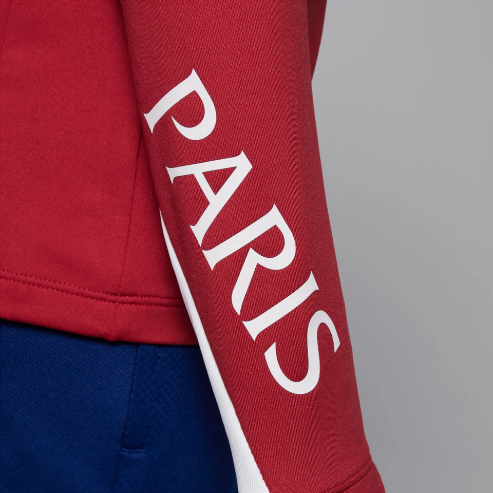Close-up of red Jordan PSG training tracksuit for kids featuring 'PARIS' text on the sleeve