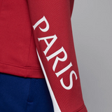 Close-up of red Jordan PSG training tracksuit for kids featuring 'PARIS' text on the sleeve