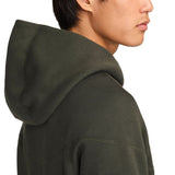 Close-up side view of a man wearing a dark green Tottenham Hotspur Nike Tech Fleece tracksuit hoodie