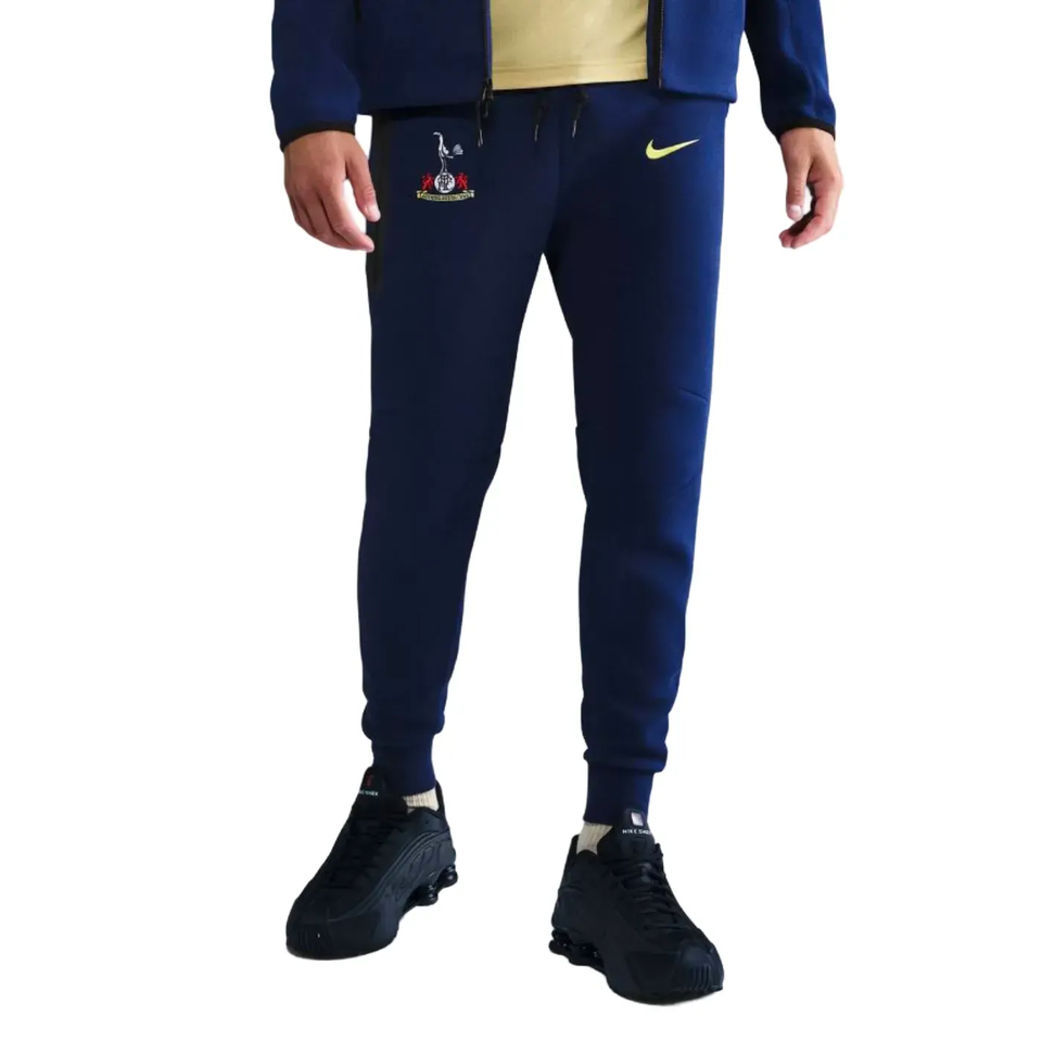 Man wearing Tottenham Hotspur UCL Tech Fleece tracksuit, featuring navy color and Nike logo