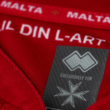 Close-up of the Malta national soccer jersey 2022 tag on a red tracksuit for soccer fans