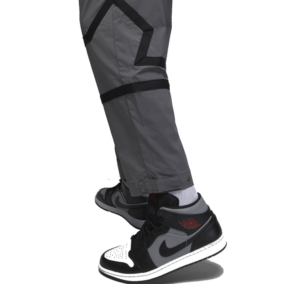 Close-up of grey Jordan PSG presentation suit pants paired with black and white Air Jordan sneakers